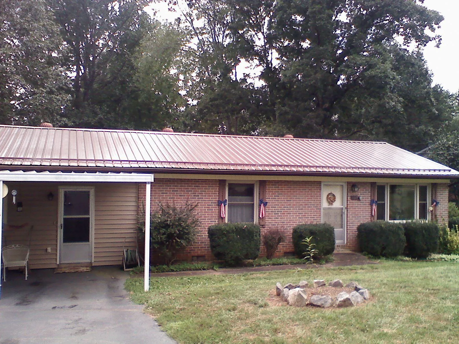 Bronze metal roof and carport on a brick ranch home — Roof Repair work by our crew in Baxter