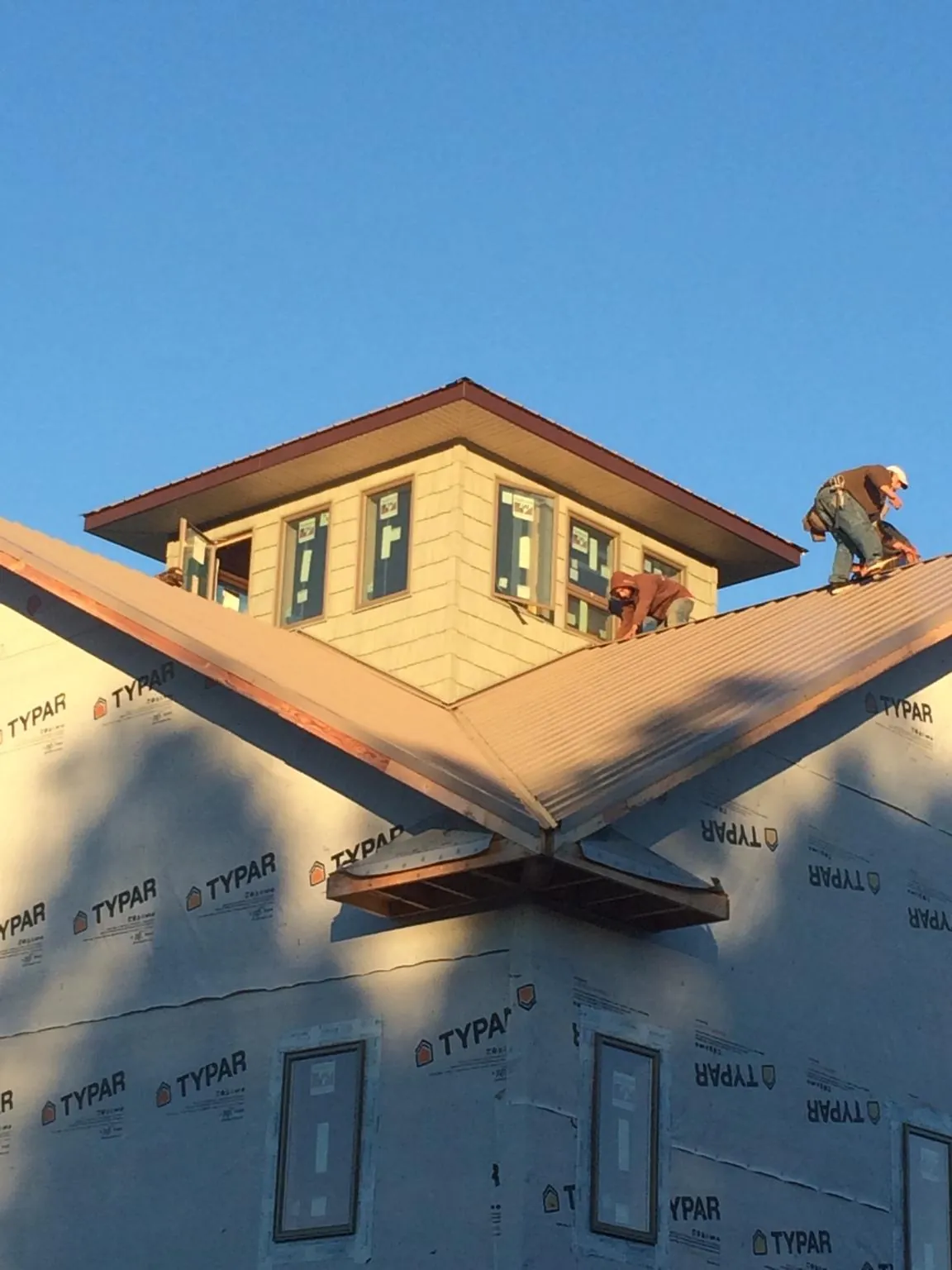 Roofers working around a rooftop cupola on a new metal roof at sunset — Roof Waterproofing in Baxter by Roofing Brothers